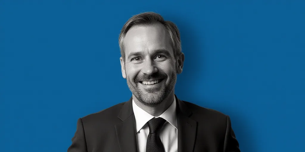 a man in a suit and tie is smiling for the camera with a blue background and a black and white photo