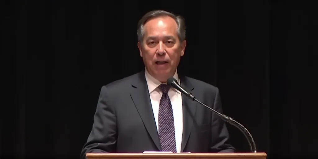 a man in a suit and tie making a speech at a podium with a microphone in front of him, Donald Roller