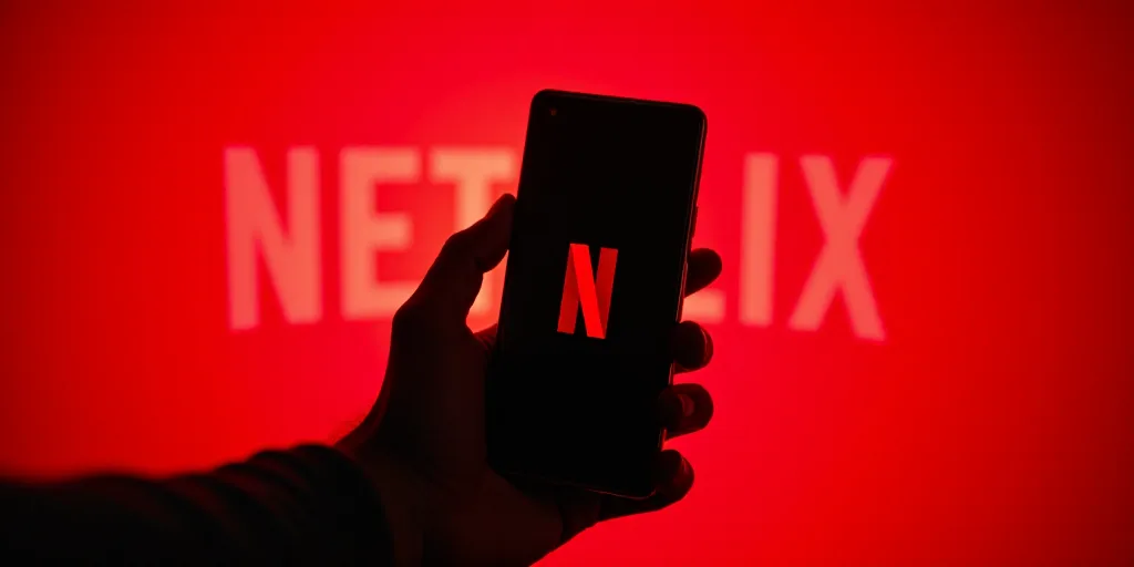 a person holding a cell phone with a netflix logo on it in front of a red background with a netflix