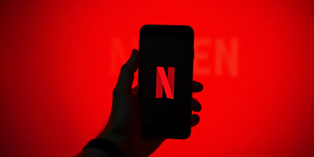a person holding a cell phone with a netflix logo on it in front of a red background with a netflix