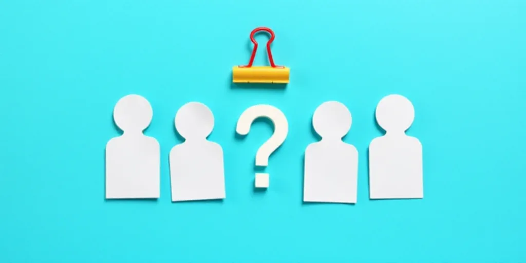 a group of paper cutouts of people and a question mark on a blue background with a red paper clip, A